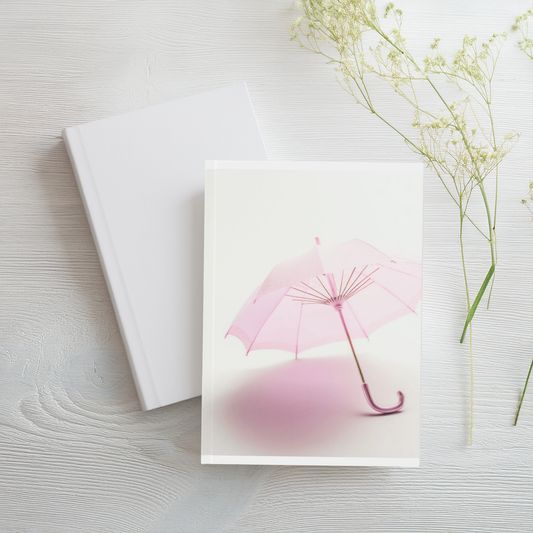 Pale pink umbrella aesthetic A5 journal styled on a wooden table with a handful of wild flowers