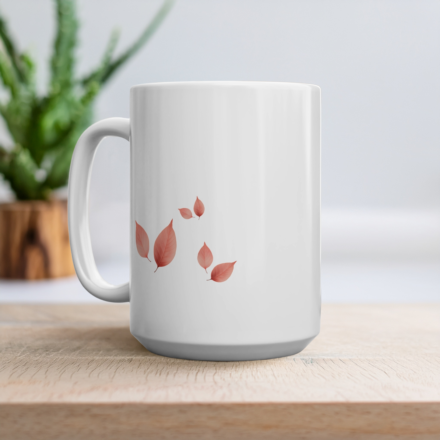 15oz mug with design of cluster of leaves on each side. The mug is on a wooden table with a plant in the background.