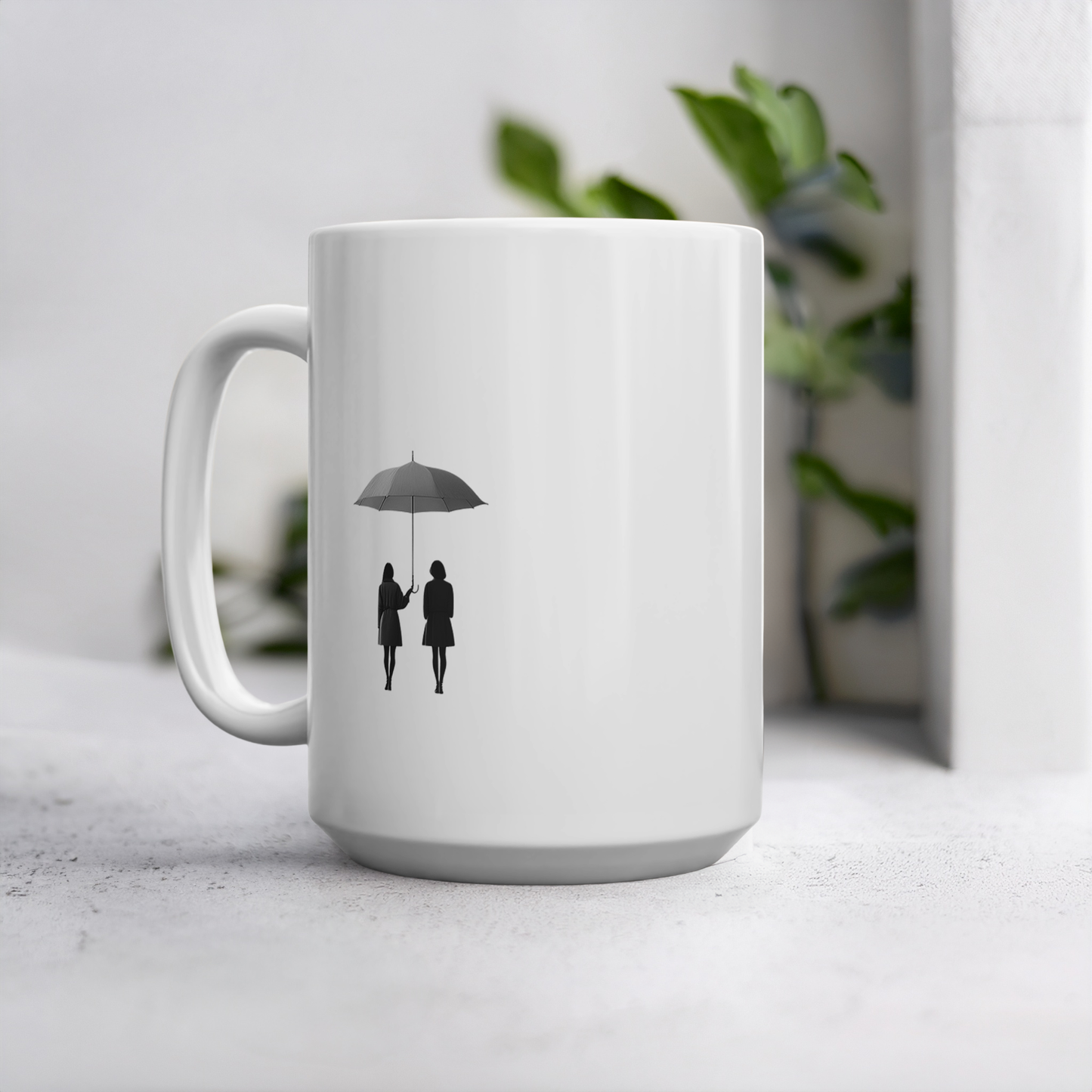 White ceramic 15oz mug with black line art illustration of two friends under an umbrella. The mug sits on a cement style surface with plant behind it.