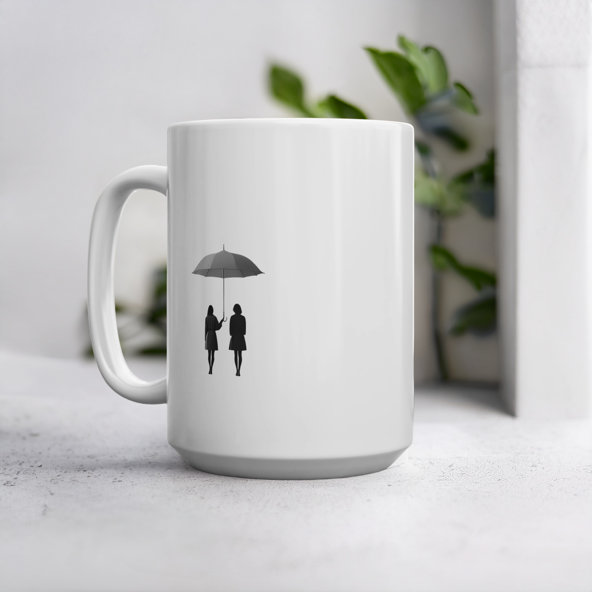 White ceramic 15oz mug with black line art illustration of two friends under an umbrella. The mug sits on a cement style surface with plant behind it.