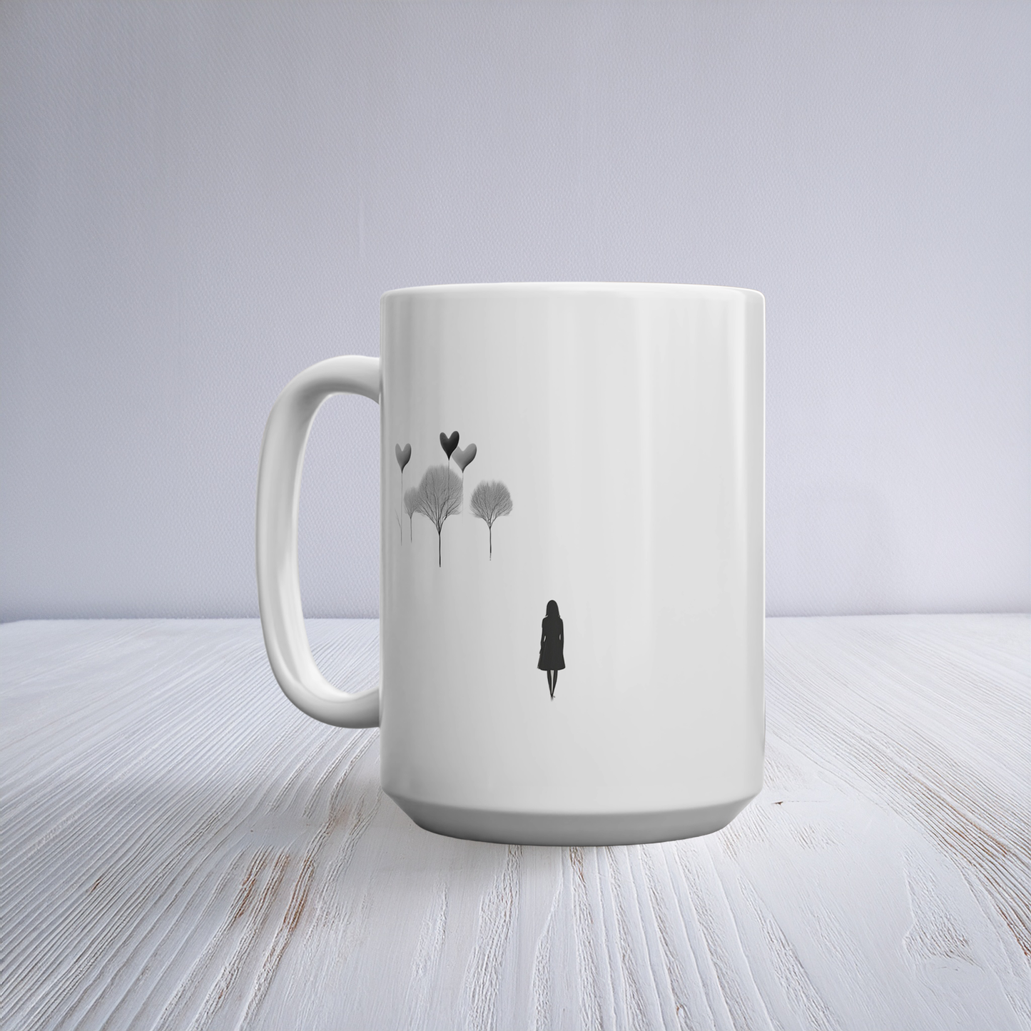 White ceramic 15oz mug with black line art illustration of woman and whimsical tree sand hearts. The mug sits on a white wooden table. 