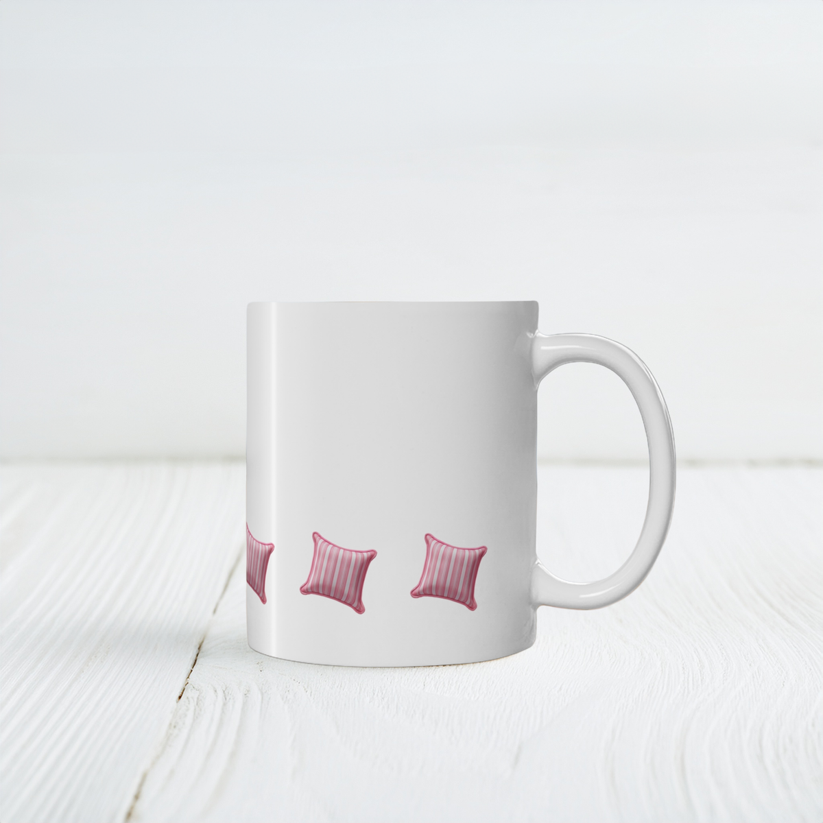 A white ceramic mug with a handle, decorated with a repeating pattern of small pink striped pillows, set on a white wooden surface against a white background.