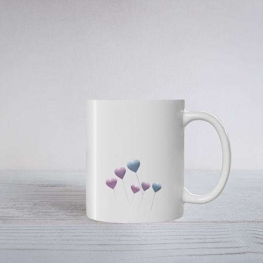 White ceramic mug with pale blue and purple floating heart design on a white wooden surface