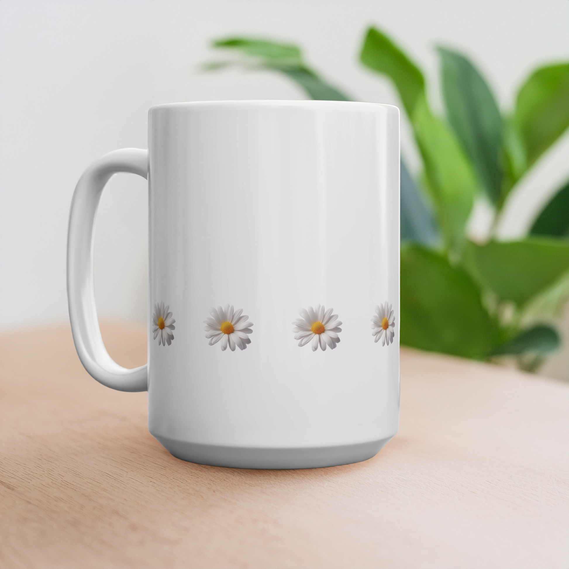 15oz mug with design of row of daisies at the bottom. The mug is on a wooden table with a plant in the background.