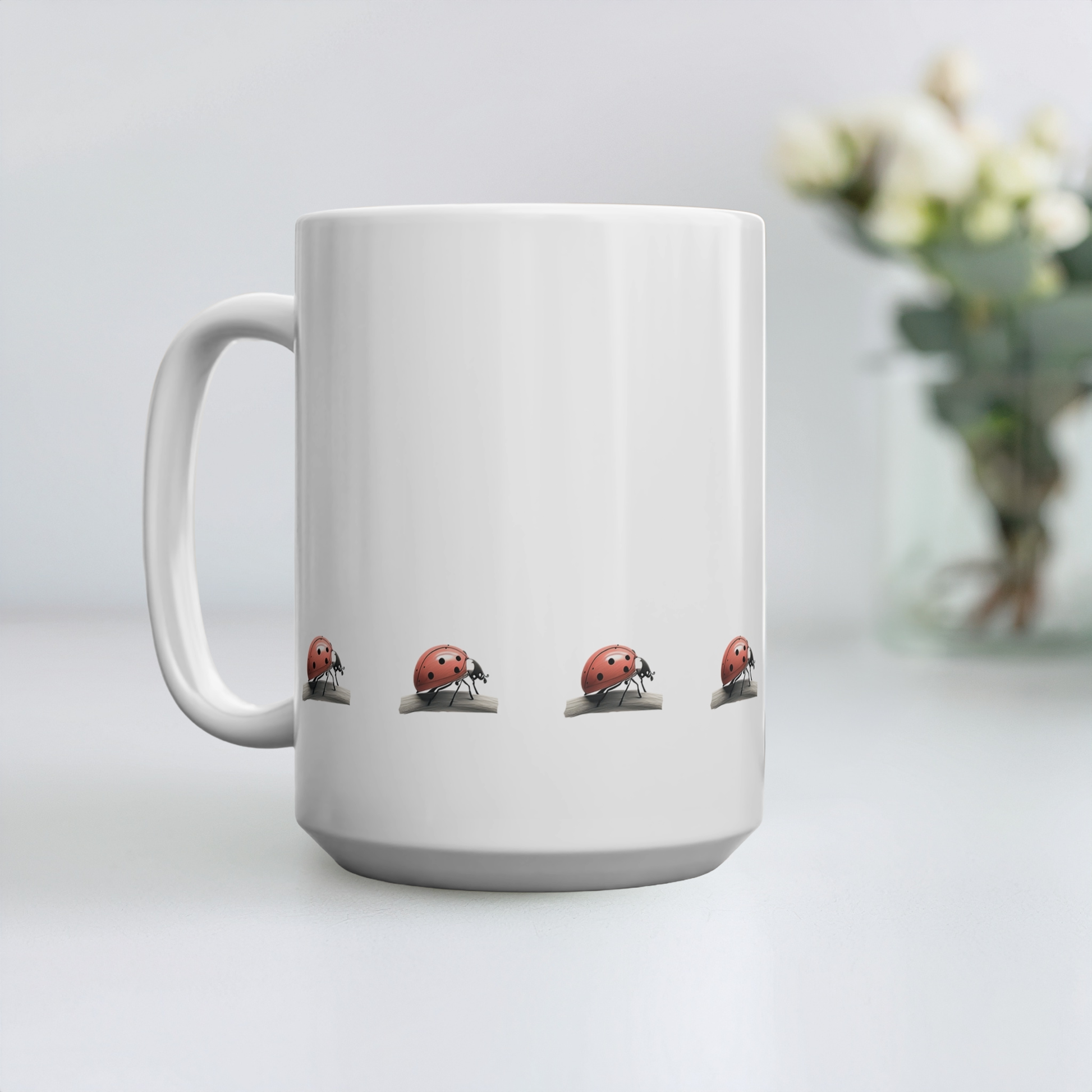 15oz mug with design of row of red ladybirds (ladybugs) at the bottom. The mug is on a table with small flowers in a vase in the background.