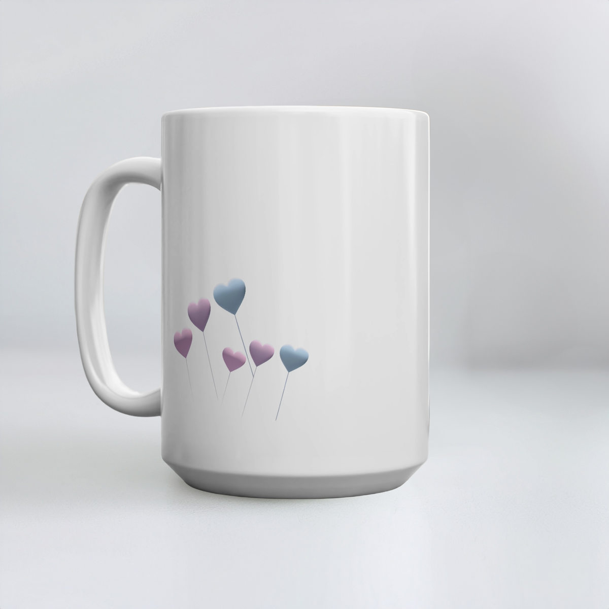 15oz white ceramic mug with pale blue and purple floating heart design on a white minimalist surface