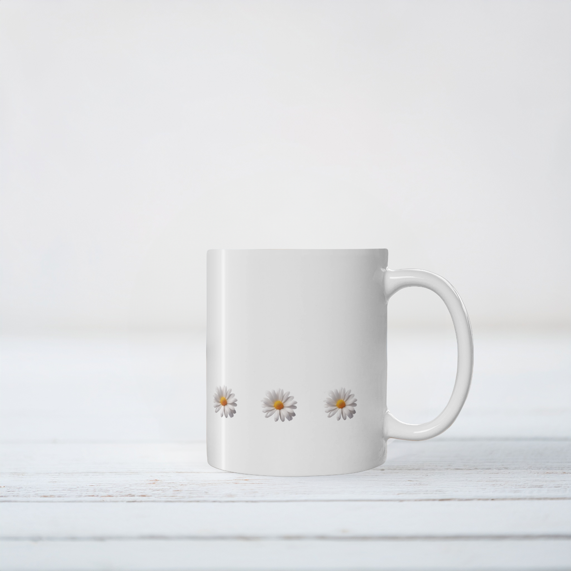 White ceramic mug with daisy design. The mug sits on white wooden surface.